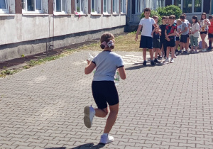 Zawody klas młodszych na szkolnym boisku – wyścigi z butelkami.