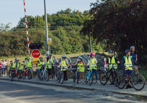 Rowerzyści prowadzą rowery poprzez przejazd rowerowy na ulicy Pienistej.