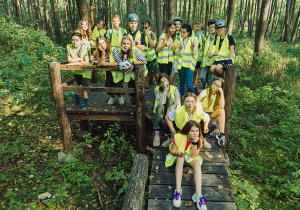 Grupowe zdjęcie uczniów klasy 7d stojących w lesie na platformie widokowej.