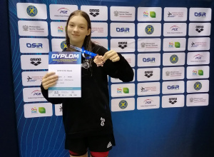 Zawodniczka Bianka Cieplucha trzyma w dłoni brązowy medal zdobyty na Zimowych Mistrzostwach Polski Juniorów młodszych w pływaniu