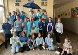 Uczniowie klasy 5c prezentują pod niebieskim parasolem portret Pani Wody symbolizującej życie.