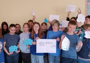 Grupa uczniów z klasy 7c w strojach w kolorze niebieskim przedstawia plakat z okazji Międzynarodowego Dnia Wody.