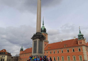 Uczestnicy wycieczki stoją pod pomnikiem króla Zygmunta III Wazy