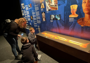 Pod lupą nauki – uczniowie pod tablicą informującą o badaniach nad mumią Tutenchamona